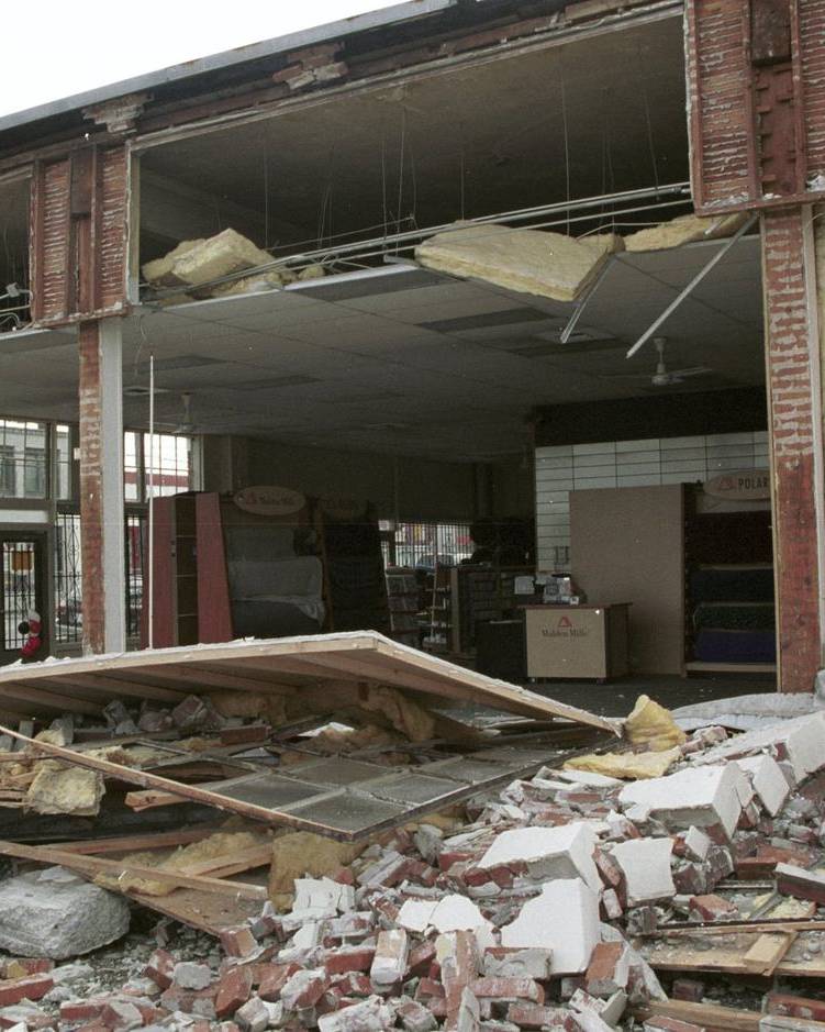 Store front torn open by earthquake damage, with rubble on the floor