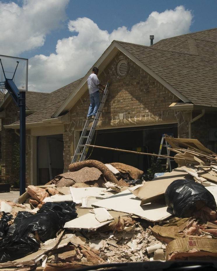 Homeowner working on his house beside a pile of flood debris